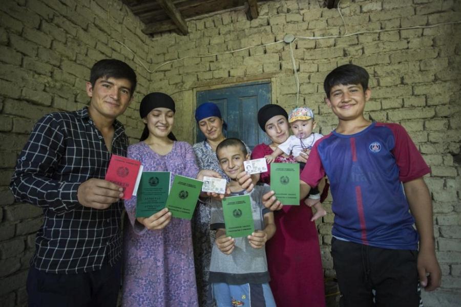 A leur domicile, les membres d’une famille anciennement apatride montrent leurs passeports récemment obtenus à Douchanbé, au Tadjikistan. © HCR/Didor Saidulloyev